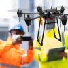 Grand Designs International drone survey team with company-branded helmet, jacket and survey drone